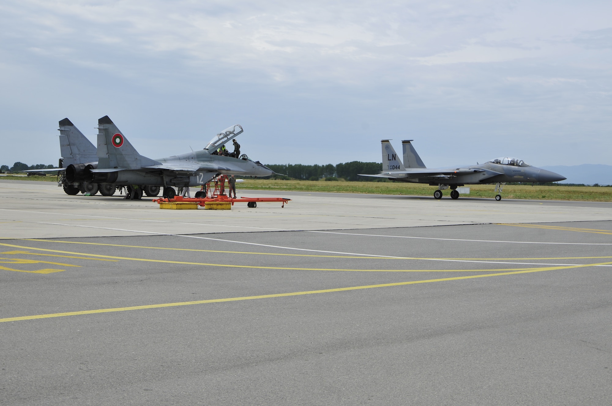 Maj. Gen. Jack Egginton, U.S. Air Forces in Europe director of air and space operations, exits a Bulgarian MiG-29 while an F-15 carrying Bulgarian air force Maj. Gen. Konstantin Popov, chief of air force training headquarters, taxis by at Graf Ignatievo Air Force Base, Bulgaria, today. The generals flew in their respective countries’ airframes to mark the end of joint-exercise Sentry Gold. The exercise was designed to continue building relationships between the two air forces and continue Bulgaria’s integration into NATO. (U.S. Air Force photo/Airman 1st Class Tiffany M. Deuel)