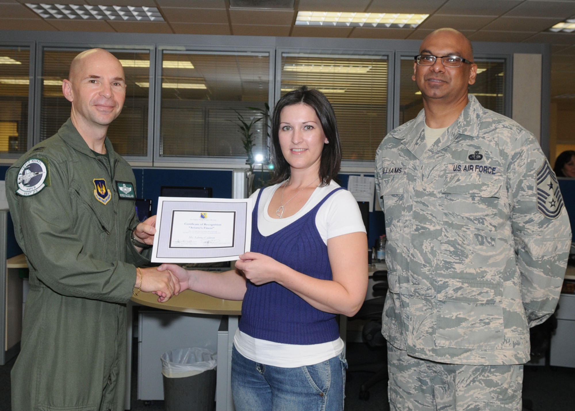 Col. Patrick A. McClelland, 31st Fighter Wing vice commander, congratulates Ms. Sabrina Calderan, 31st Comptroller Squadron, civilian pay technician, on her selection as one of Aviano's Finest as Chief Master Sgt. Laten Williams, 31st FW command chief, looks on. 
(U.S. Air Force photo/Staff Sgt. MercedesKimble Crossland)