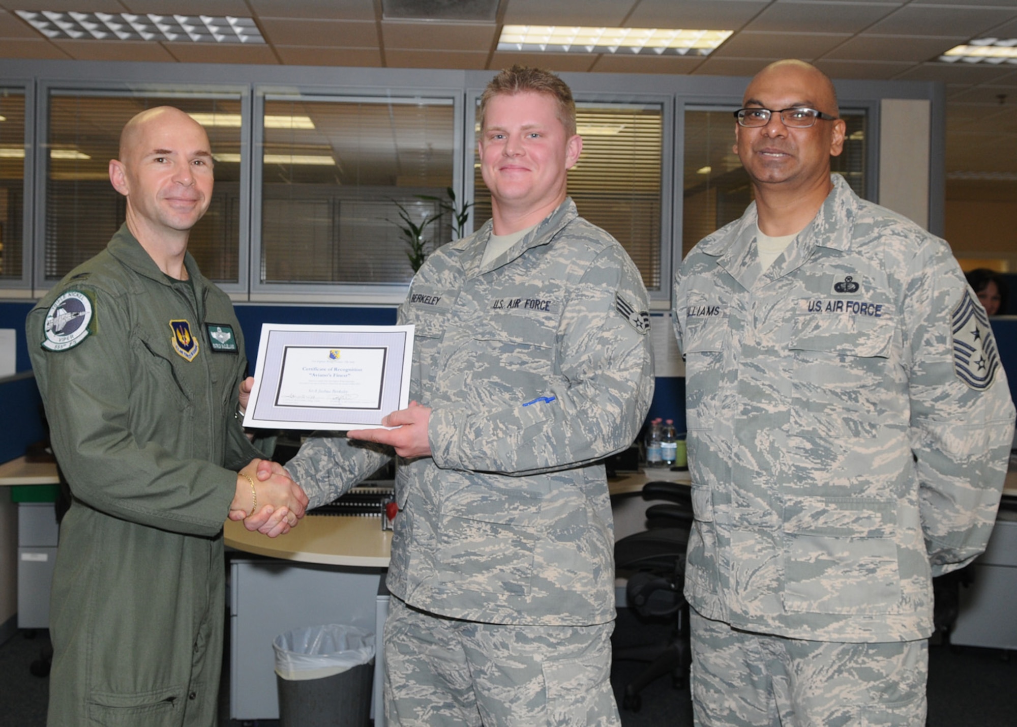 Col. Patrick A. McClelland, 31st Fighter Wing vice commander, congratulates Senior Airman Joshua Berkeley, 31st Comptroller Squadron, travel technician, on his selection as one of Aviano's Finest as Chief Master Sgt. Laten Williams, 31st FW command chief, looks on. 