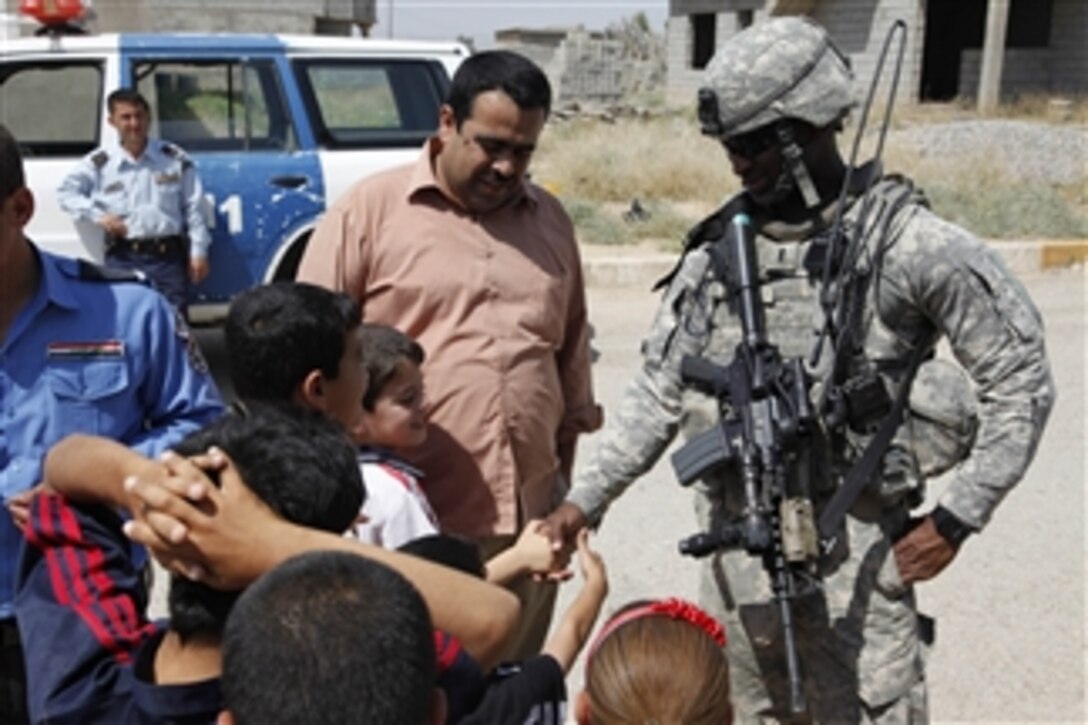 U.S. Army 1st Lt. Jeremy Lewis, platoon leader, 3rd Platoon, Bravo Battery, 2nd Battalion, 3rd Field Artillery Regiment, 1st Heavy Brigade Combat Team, 1st Armored Division, shakes hands with local children during a visit to a village near Kirkuk, Iraq, on May 8, 2010.  U.S. soldiers visited villages around Kirkuk to gather atmospherics by meeting and speaking with the locals about current conditions in the area.  