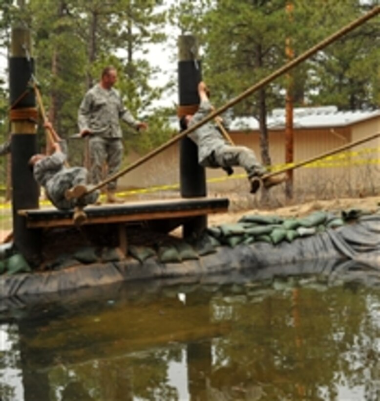 U.S. Air Force Tech. Sgt. Leslee Williams (left) goes hand-over-hand on a rope over a water hazard as Staff Sgt. Alex Andriyanov (right) reaches the end of his rope during a practice run on an obstacle course at the U.S. Air Force Academy in Colorado on May 18, 2010.  Both airmen, who are assigned to the Space and Missile Systems Center's 61st Security Forces Squadron out of Los Angeles Air Force Base, are competing in Guardian Challenge 2010, Air Force Space Command’s biennial space and cyberspace competition.  