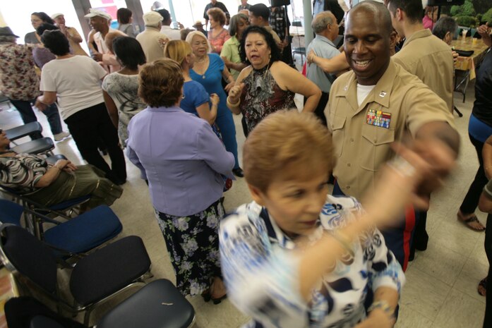 NEW YORK -- Capt. Afinju McDowell, movement control officer-in-charge of SPMAGTF NY, dances with a lady from Williamsburg Senior Center. Several service members from the amphibious assault ship USS Iwo Jima, and Special Purpose Marine Air-Ground Task Force New York, visited with some of New York's senior citizens at the Jewish Association for Services for the Aged program's Williamsburg Senior Center in Brooklyn, N.Y., May 28, 2010, as part of Fleet Week New York's community outreach projects.ore than 3,000 Marines, Sailors and Coast Guardsmen are in the area participating in community outreach events and equipment demonstrations. This is the 26th year New York City has hosted the sea services for Fleet Week.
