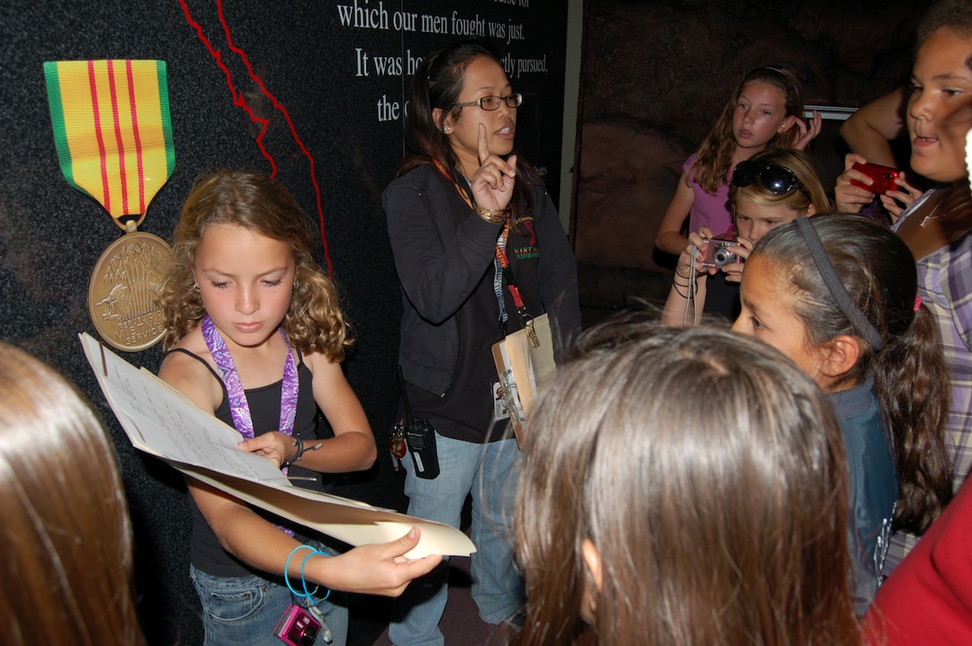 Many Chea, center, a student intern with the Marine Corps Recruit Depot Command Museum, shares Marine Corps historical information with students from Oliver Wendell Holmes Elementary School May 28, here. More than 30 students, parents and teachers from the school toured the depot as part of a Partnership in Education program that supports student achievement and fosters community collaborations throughout the San Diego area.