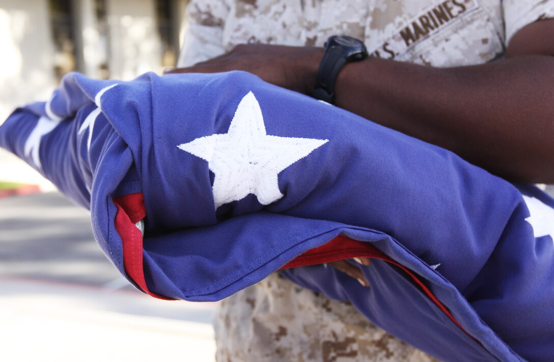 Lance Cpl. Clarance Gilbert, food service specialist, 1st Marine Logistics Group, holds a flag in preparation for the morning flag raising ceremony at building 1160, May 28. Marines traditionally perform the ceremony on a daily basis at 8 a.m. On Memorial Day, the flag is flown half-staff until noon, in honor of America’s fallen heroes.