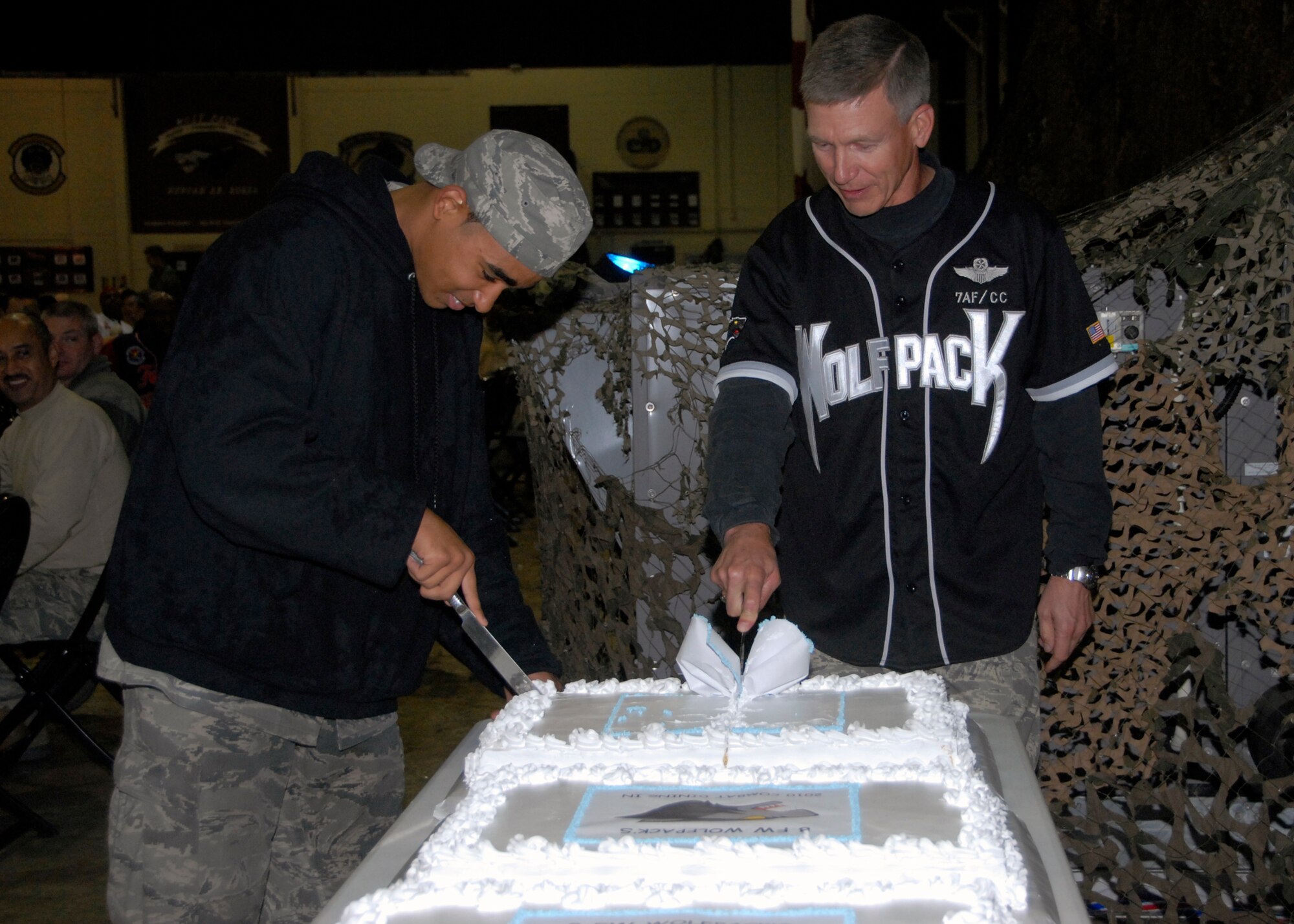 Lt. Gen. Jeffrey Remington, 7th Air Force commander and prior Wolf Pack member, and Airman 1st Class Zachary Tealer, 8th Security Forces Squadron, work together to cut the cake at the Combat Dining-In here Oct. 30.  Airman Tealer was selected to cut the cake with the general because he was the youngest Airman in attendance.   (U.S. Air Force photo/Capt. Sheryll Klinkel)
