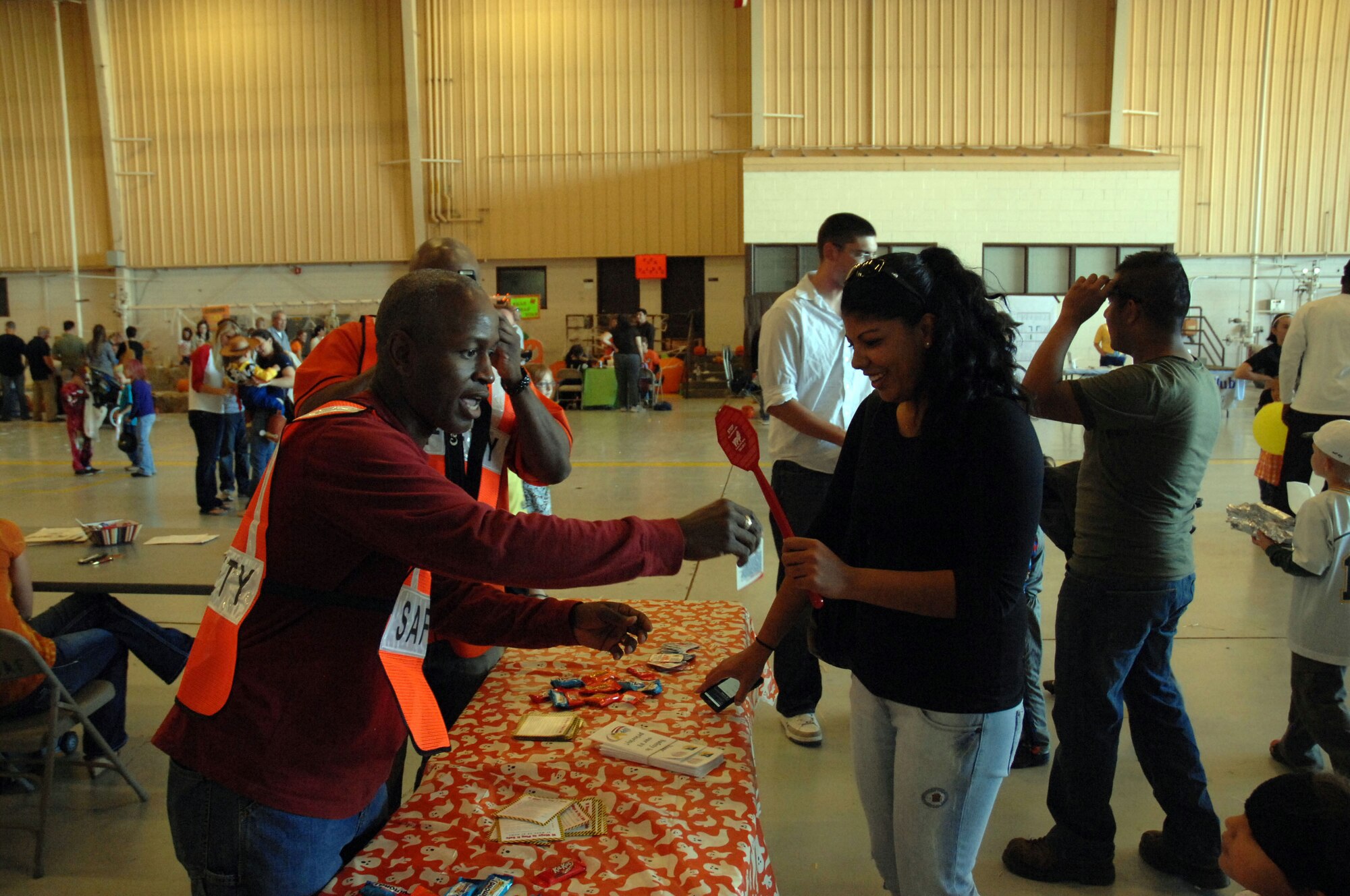Senior Master Sgt. Drake Davidson (left), 27th Special Operations Wing Safety, hands out items to Senior Airman Michelle Garcia, 27th Special Operations Comptroller Squadron, during the fall festival held in Hangar 208 here October 30. The event featured aircraft displays, food, games, information booths and more. (U.S. Air Force photo by Senior Airman Elliott Sprehe)
