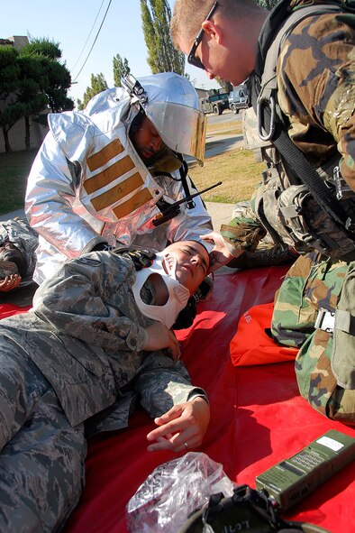 Senior Airman Timothy Sherrod, 51st Civil Engineer Squadron, and Airman 1st Class Gerald Lombardi, 51st Security Forces Squadron, apply a neck brace to a simulated victim injured in a major vehicle accident scenario Nov. 1 at Osan Air Base, Republic of Korea, during exercise Beverly Midnight 10-02. The exercise allows Airmen to demonstrate their ability to complete the mission in simulated chemical environments while executing their primary duties, practicing self aid and buddy care, conducting post-attack reconnaissance and unexploded ordnance sweeps. (U.S. Air Force photo/Staff Sgt. Eunique Stevens)