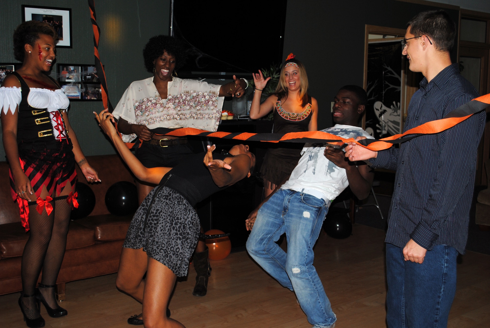 Airmen cheer as Senior Airman Dynesha Adams leans into a limbo during the ‘How low can you go’ competition at the Airman’s Council Halloween party Oct. 22.(U.S. Air Force photo/Airman 1st Class Kristina Overton)