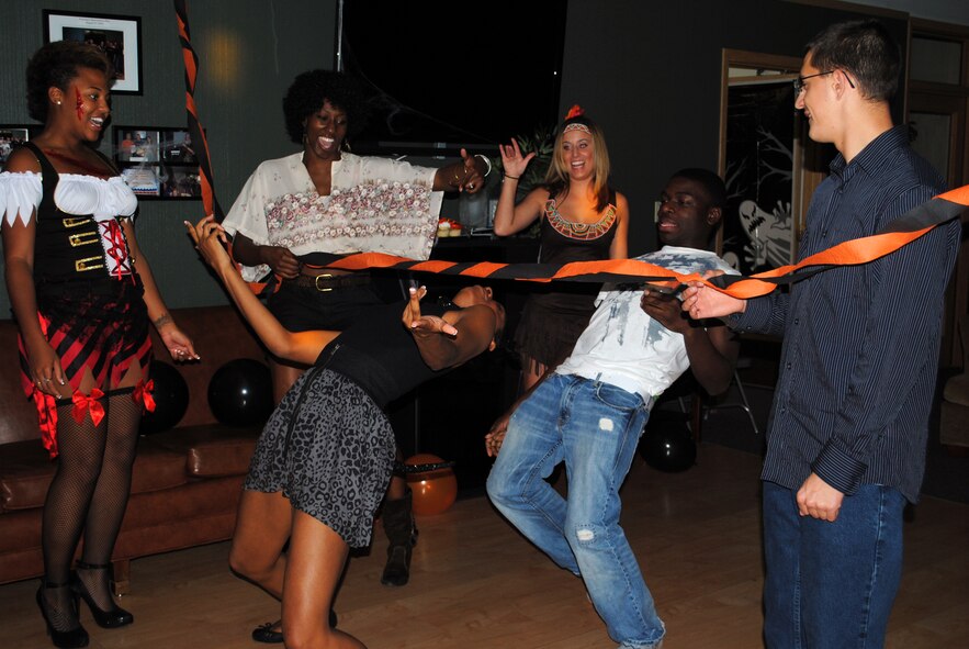 Airmen cheer as Senior Airman Dynesha Adams leans into a limbo during the ‘How low can you go’ competition at the Airman’s Council Halloween party Oct. 22.(U.S. Air Force photo/Airman 1st Class Kristina Overton)