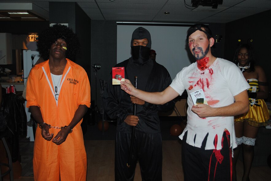 Airman 1st Class Zachary Freeman, 341st Medical Operation Squadron flight medic, right, prepares to announce the winner of the Halloween costume contest at the Airman’s Council Halloween party Oct. 22. The crowd favorites were Airman 1st Class Quentin Gilmore, 341st Operations Group knowledge operator, left, and Airman 1st Class Jonathan Greene, 341st Force Support Squadron reenlistments technician, but ultimately Airman Greene sliced through the competition for the $50 grand prize.(U.S. Air Force photo/Airman 1st Class Kristina Overton)
