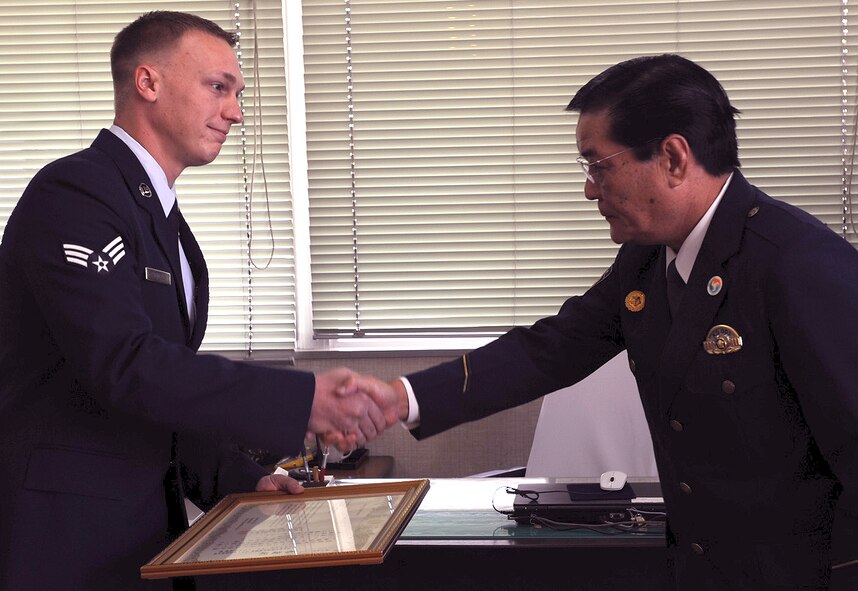 KADENA TOWN, Japan -- (Left) Senior Airman Richard Howell accepts a certificate of appreciation from the Kadena Town chief of police during a formal recognition ceremony at the police station near Kadena Air Base, Nov. 1. The senior airman from the 961st Airborne Air Control Squadron helped save the life of a local boy who went unconscious and nearly drowned while snorkeling with his father. The boy and his family also wrote thank you letters to the Airman for his heroic efforts. (U.S. Air Force photo by Junko Kinjo)