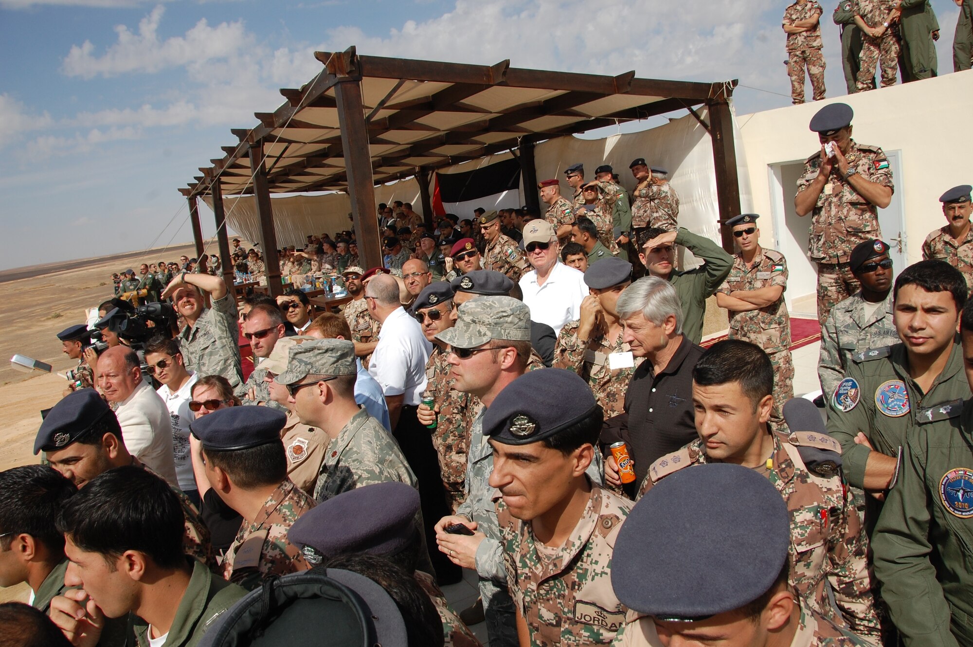 A group of multinational Airmen watch a live fire event at Falcon Air Meet in Azraq, Jordan, from a rooftop. Lt. Gen. Mike Hostage, U.S. Air Forces Central Command commander was hosted by Prince Faisal bin Al Hussein of Jordan at the event. About 250 Airmen from all over the world came to Jordan for the two week meet that ran Oct. 19 to Nov. 2. This is the fourth year the Americans have participated. The U.S. Air Force, Pakistani Air Force and the United Arab Emirates Air Force were hosted by the Royal Jordanian Air Force for the meet.  (U.S. Air Force Photo by Mr. Alan Black)
