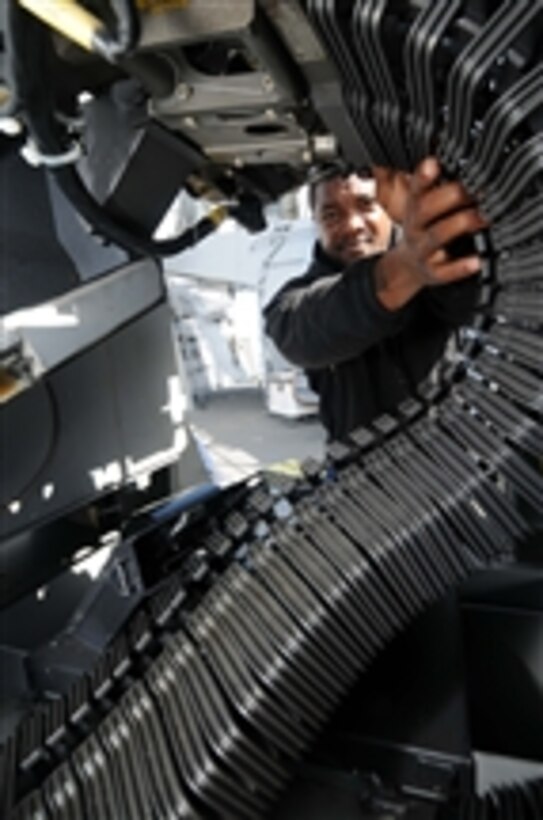 U.S. Navy Petty Officer 2nd Class Terrance Davis, assigned to the guided missile destroyer USS Mitscher (DDG 57), loads a MK-38 machine gun while underway in the Atlantic Ocean on Oct 26, 2010.  The Mitscher is part of the George H.W. Bush (CVN 77) Carrier Strike Group that is participating in a sink exercise, a weapons system test involving a torpedo or missile attack of an unmanned target ship.  