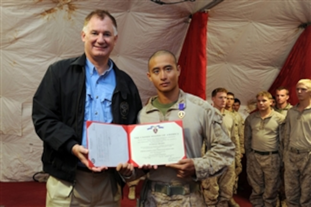 Deputy Secretary of Defense William J. Lynn III poses with Cpl. Jackson Hester after presenting him a purple heart for wounds received in Afghanistan on Oct. 28, 2010.  