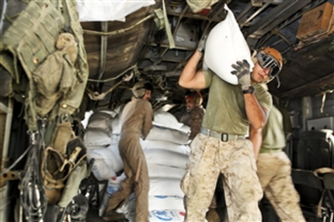 U.S. Marine Corps Lance Cpl. Christian Vaca carries a bag of wheat flour to a Pakistan military member while off-loading relief supplies to Hassan Khan Jamali, Pakistan, Nov. 1, 2010. With the Pakistan military, U.S. Marines have transported more than 3.7 million pounds of supplies to 150 locations in southern Pakistan. Vaca is a power plants mechanic assigned to Marine Medium Tiltrotor Squadron 266, 26th Marine Expeditionary Unit.