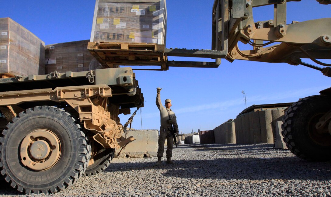 Cpl. Francisco Brito, vehicle operator, 2nd Platoon, Motor Transport Company A, Combat Logistics Battalion 3, 1st Marine Logistics Group (Forward), directs a material handling equipment operator aboard Forward Operating Base Delhi, Nov. 1. The Marines and sailors of CLB-3's two motor transport companies are tasked with providing combat logistics support to units within Regimental Combat Team 1.