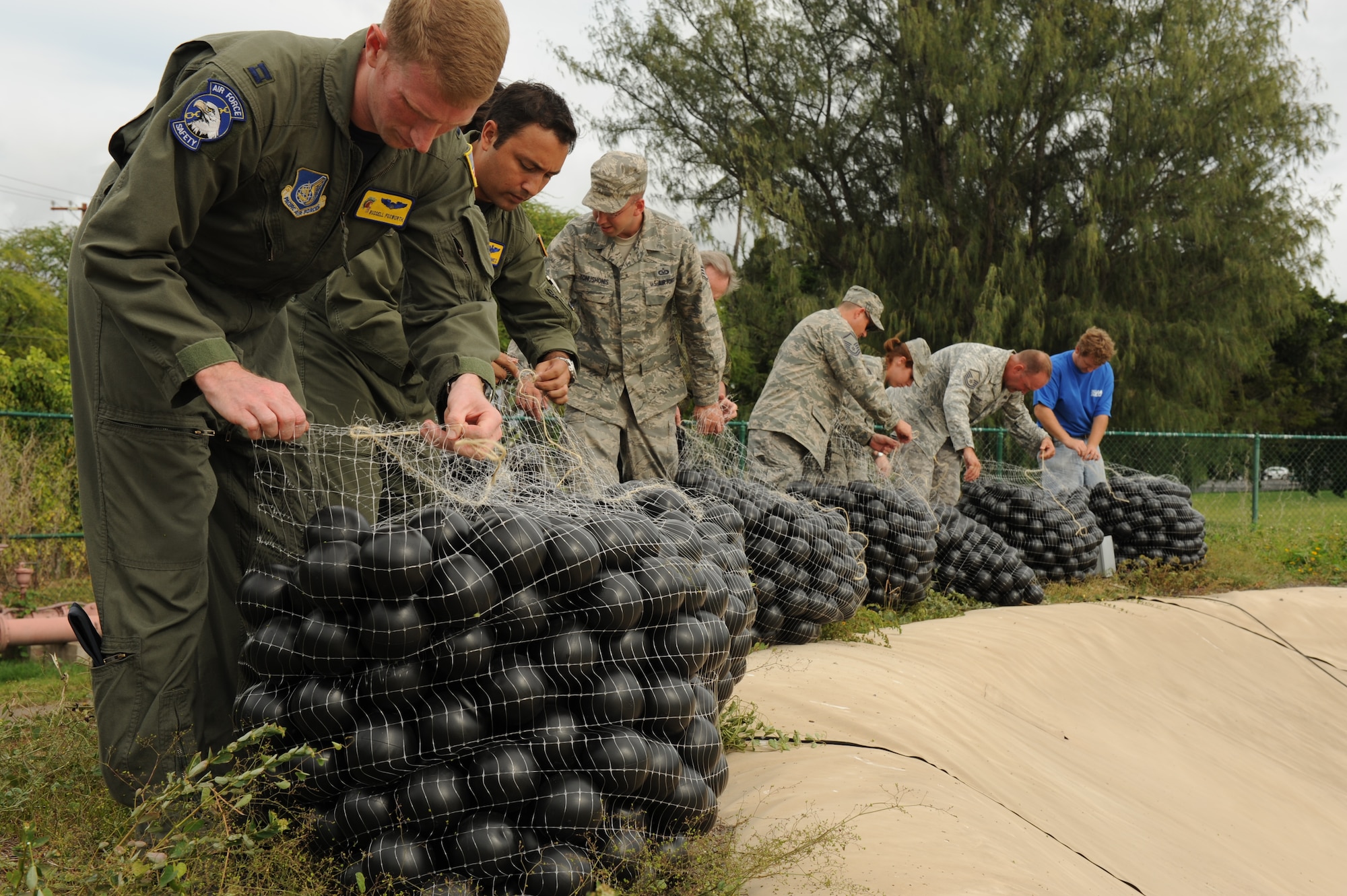 JOINT BASE PEARL HARBOR-HICKAM, Hawaii - Members of 647th Services Squadron, 647th Contracting Squadron, 15th Wing safety office and Mamala Bay Golf Course workers release more than 70,000 “Armor Balls” into the Mamala Bay Golf Course reservoir here, Oct. 26. The Bird Hazard Working Group initiated the bird hazard abatement as part of the Bird/Wildlife Aircraft Strike Hazard, also known as the BASH program, to help reduce bird strike incidents with aircraft. (U.S. Air Force photo/Senior Airman Gustavo Gonzalez)
 