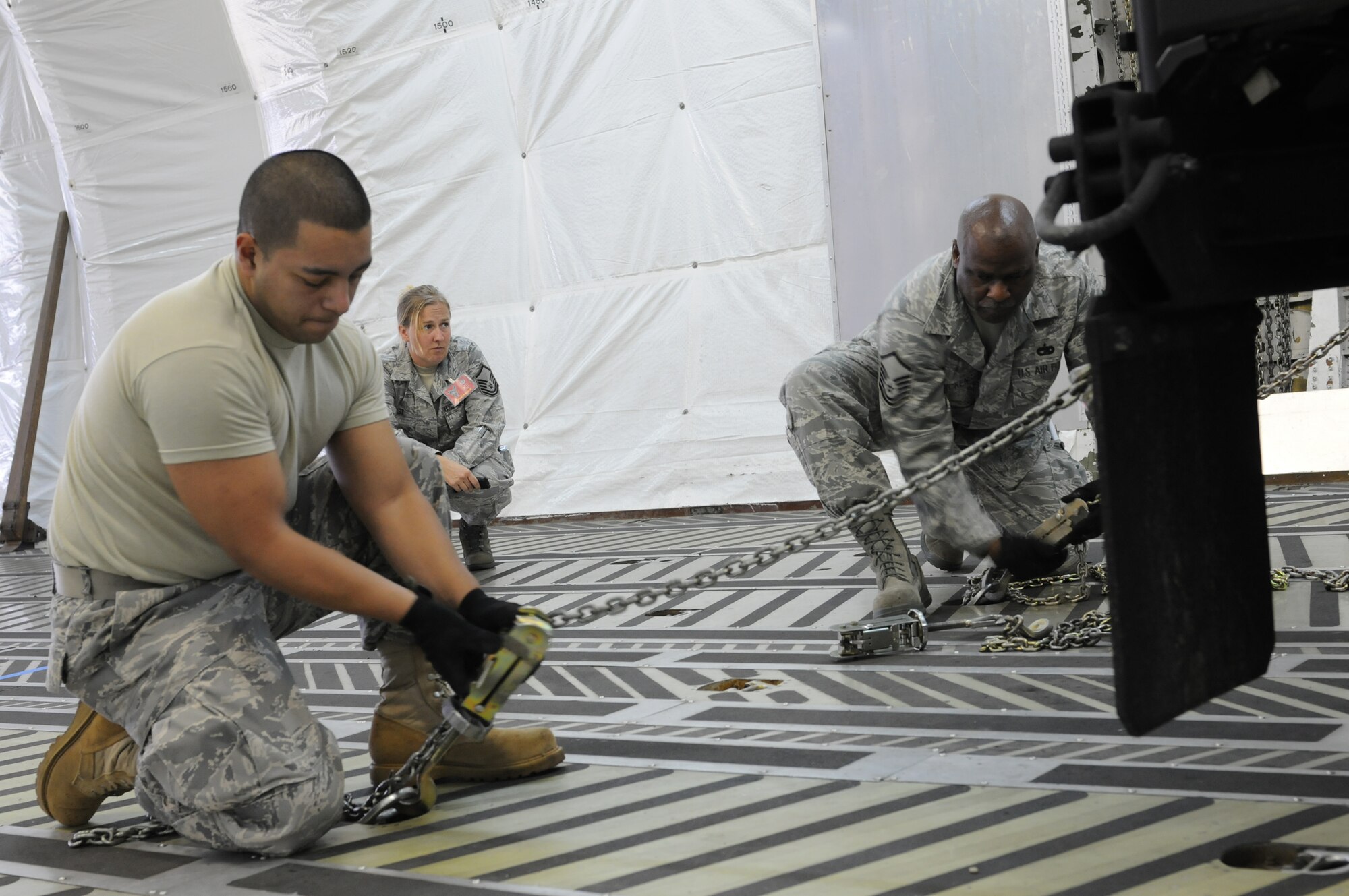 DOBBINS AIR RESERVE BASE, Ga. -- Staff Sgt. Diego Jainez (left) and Master Sgt. Tim Dickens (right), 69th Aerial Port Squadron, use chains to secure a humvee as Master Sgt. Bonnie Bast, 22nd Air Force umpire, observes in a competition event at the Air Force Reserve Command's Port Dawg Challenge here Oct. 27. The inaugural event pitted 23 different Reserve units against each other in a weeklong competition that tested the skills of aerial port Airmen. (U.S. Air Force photo/Tech. Sgt. Steve Lewis)