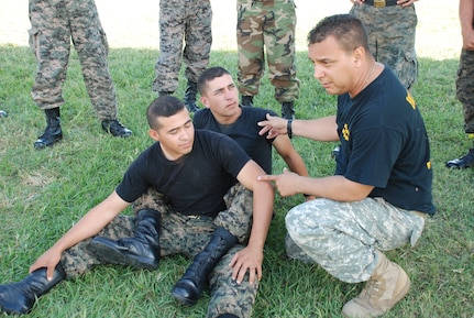 SOTO CANO AIR BASE, Honduras --  Staff Sgt. Marcos DeJesus, an Army Combatives instructor, explains offensive and defensive ground fighting techniques to members of "La Guardia," the a Honduran Security Force unit that provides both entry control and perimeter surveillance here, during joint training Oct. 28. (U.S. Air Force photo/Capt. John Stamm)