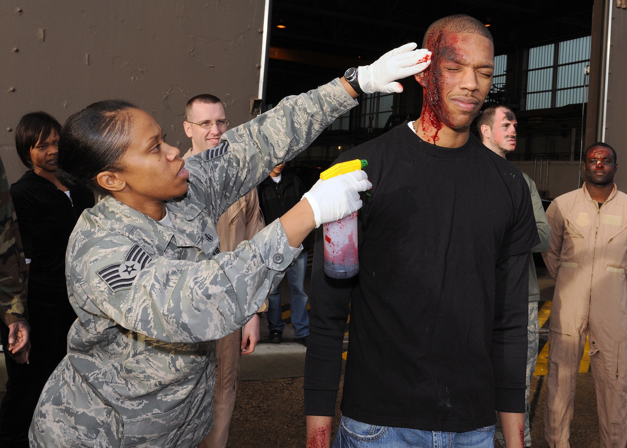 RAF MILDENHALL, England - Tech. Sgt. Candice Boykin, 48th Medical Support Squadron medical logistic war reserve material supervisor, sprays artificial blood onto the mock lacerations of Staff Sgt. Tyrece Robertson, 100th Logistics Readiness Squadron customer service technician here, Nov. 2, 2010.  This MARE was used to prepare RAF Mildenhall firefighters for real world aircraft mishaps.  (U.S. Air Force photo/Senior Airman Tabitha M. Lee)