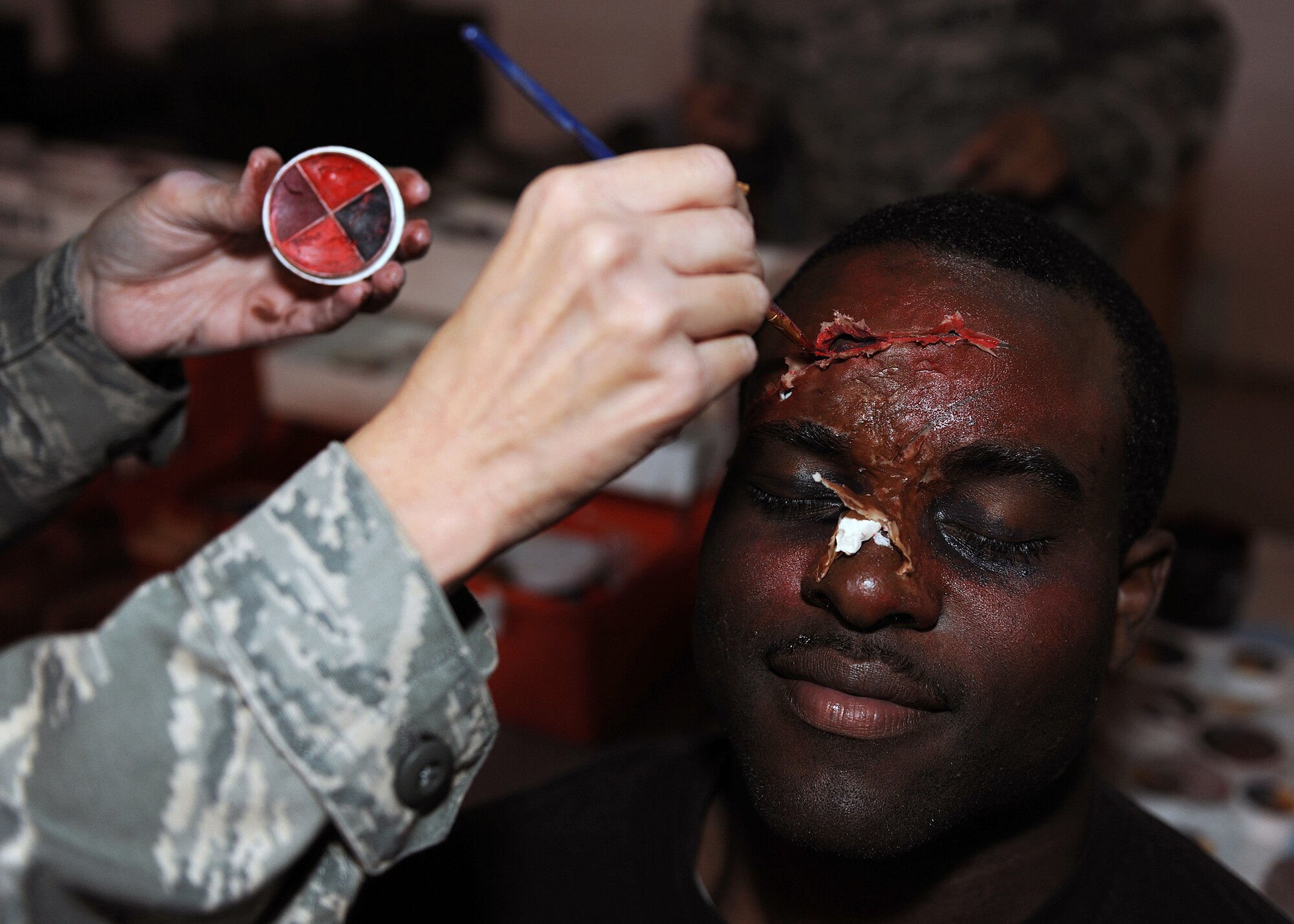 RAF MILDENHALL, England - Tech. Sgt. Michelle Linn, 48th Medical Support Squadron Educational and Developmental Intervention Services Clinic NCO in charge, applies face paint to fake lacerations on Staff Sgt. Dustin Hicks, 100th Communications Squadron postal clerk here, Nov. 2, 2010, before the Major Accident Response Exercise.  Medical personnel applied moulage, premade rubber or latex "wounds" as well as complex make-up and theater techniques, to casualty volunteers to provide elements of realism to the MARE.  (U.S. Air Force photo/Senior Airman Tabitha M. Lee)    