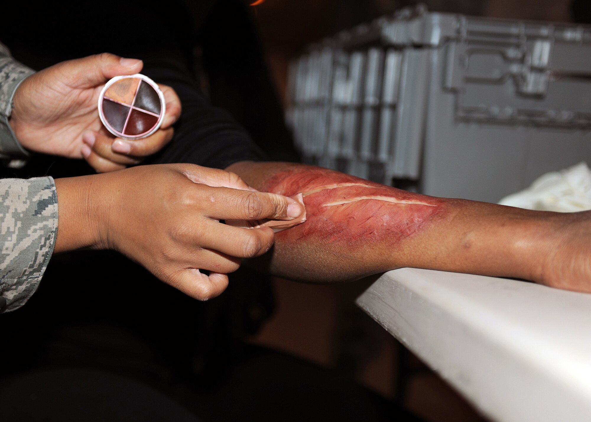 RAF MILDENHALL, England - Tech. Sgt. Candice Boykin, 48th Medical Support Squadron medical logistic war reserve material supervisor, applies moulage to the arm of a casualty volunteer here, Nov. 2, 2010.  Volunteers dressed up as casualties to give the training a more realistic experience for the emergency response personnel.  (U.S. Air Force photo/Senior Airman Tabitha M. Lee)  