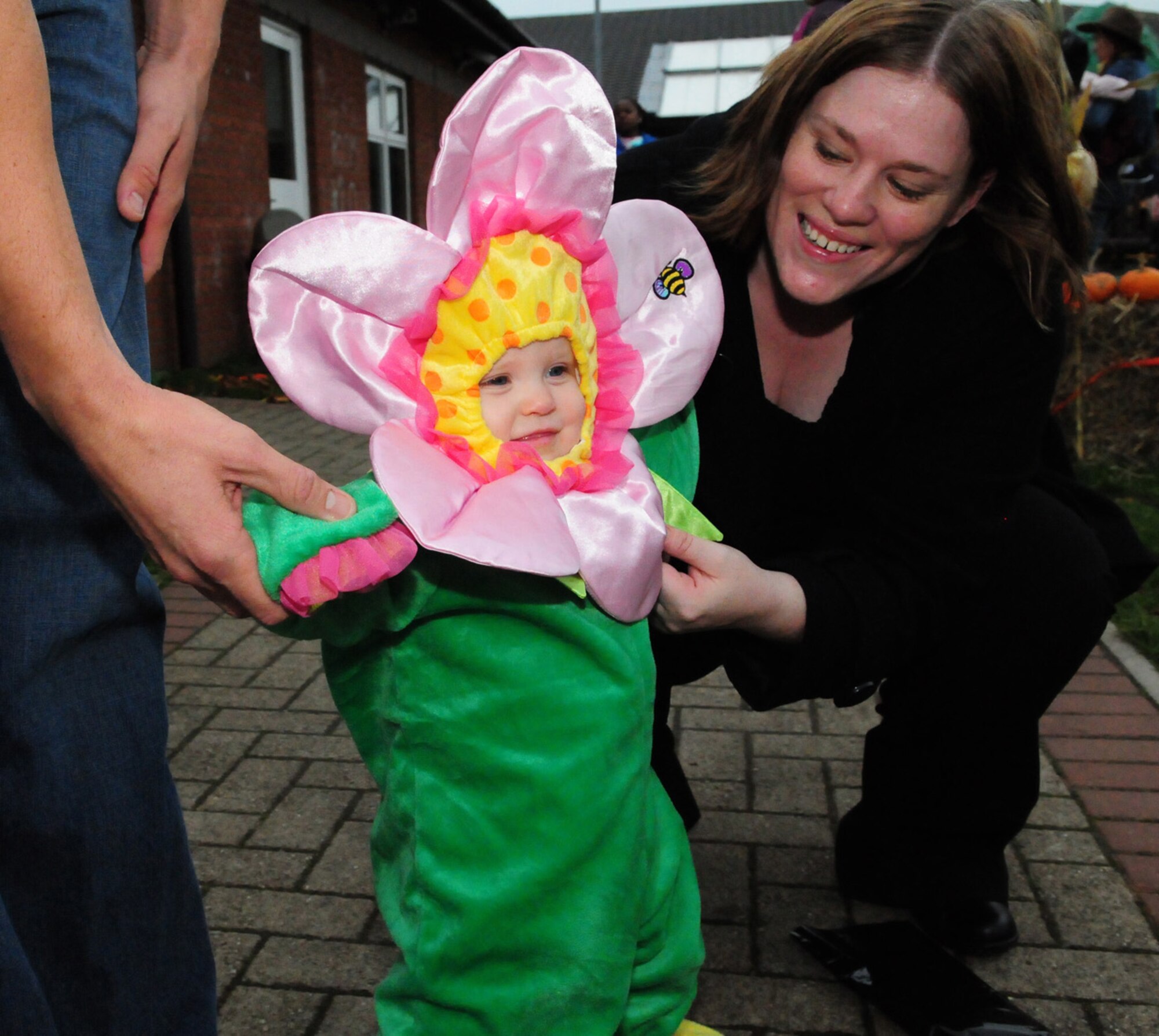 RAF MILDENHALL, England -- Lorelei Wendt, 11 months, shows off her flower power at the child development center's Fall Festival Oct. 29, 2010, as her mom Kathleen Wendt, and dad, Staff Sgt. Joe Wendt, 48th Force Support Squadron, help keep her "roots" on the ground before checking out the pumpkin patch. (U.S. Air Force photo/Karen Abeyasekere)