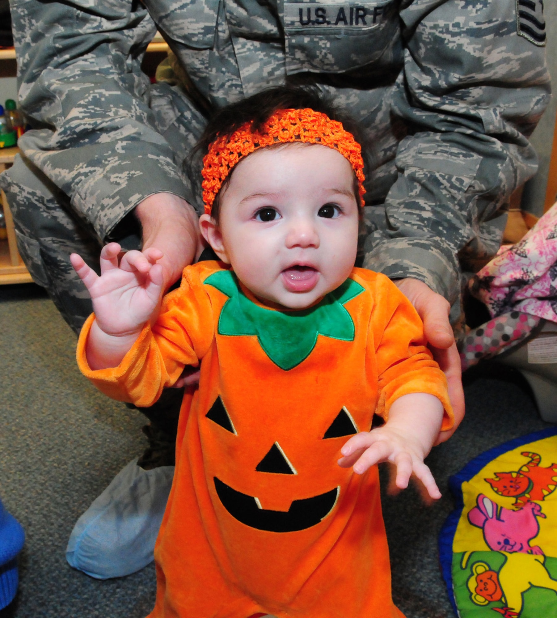 RAF MILDENHALL, England -- Kayla Lovegreen, 4 months, is held up by her dad, Master Sgt. Nicholas Lovegreen, 352nd Special Operations Maintenance Squadron, as her mom, Tech. Sgt. Rosa Lovegreen, 7th Special Operation Squadron, paints Kayla's feet before standing her on a piece of paper. This was just one of the many activities at the Fall Festival  held at the child development center Oct. 29, 2010. (U.S. Air Force photo/Karen Abeyasekere)