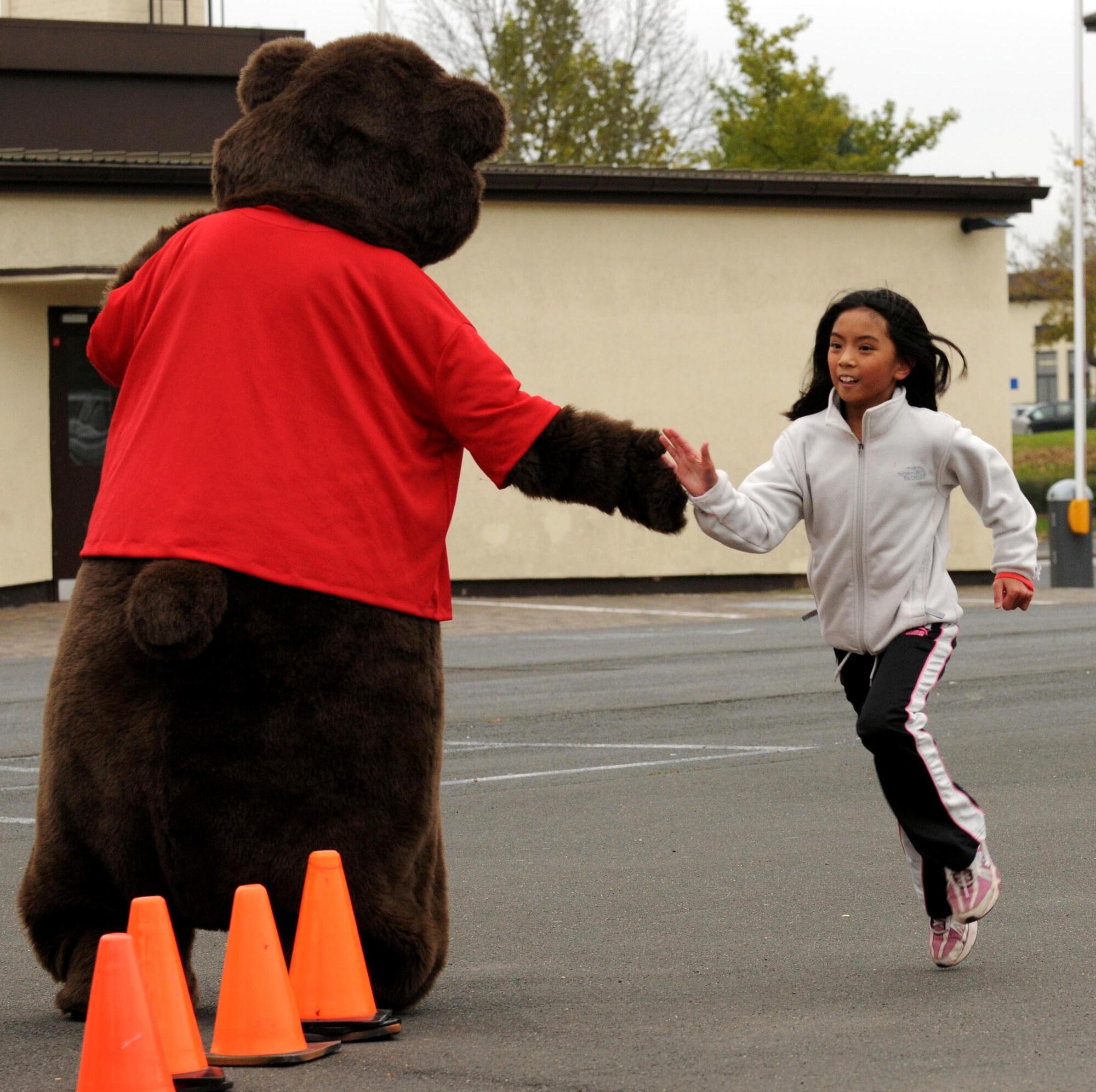 SPANGDAHLEM AIR BASE, Germany – The Drug Free Bear congratulates Emily Nop, Bitburg Middle School student, as she finishes a one-mile fun run at the Bitburg Middle School Oct. 28. The Red Ribbon Week fun run helped raise awareness about the dangers of drug and alcohol abuse. (U.S. Air Force photo/Airman 1st Class Matthew B. Fredericks)