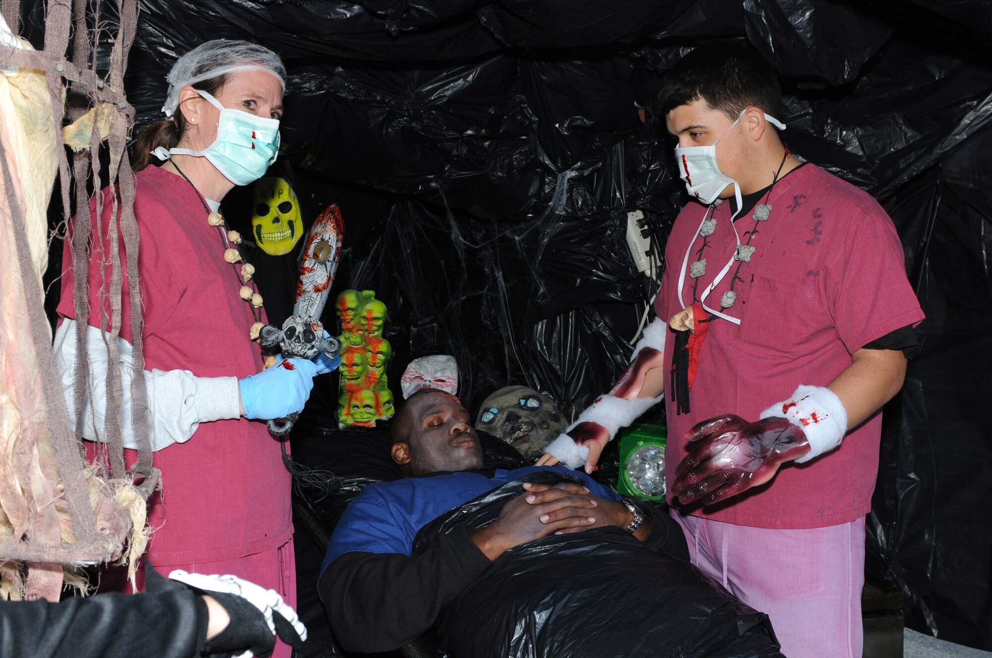Lt. Col. Virginia Garner, 31st Surgical Operations commander, and Patrick Plaza, Aviano High School senior, "operate" on Tech. Sgt. Robert Barton, 31st SGC diagnostic imaging quality control technologist, during the annual Trunk-or-Treat Oct. 30 on Capt. Gori Road. The 31st SGC received third place for the best trunk contest. (U.S. Air Force photo/Staff Sgt. Julius Delos Reyes)