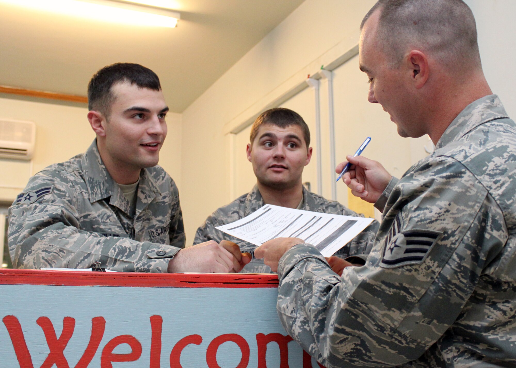 Airman 1st Class Richard Miller (left) and Senior Airman Jason Adams, 332nd Expeditionary Communications Squadron Communications Focal Point technicians, assist a customer with some paperwork at the Help Desk Oct. 19, 2010, Joint Base Balad, Iraq.  These Airmen, Soldiers and civilians are the “gatekeepers” to every communication bit, wave and 01010101-sequence support request on Balad. Airman Miller, a native of Rochester Hills, Mich., is deployed from Eglin Air Force Base, Alaska; and Airman Adams, a native of Springfield, Ohio, is deployed from Springfield Air National Guard Base, Ohio. (U.S. Air Force photo/Tech. Sgt. Stacy Fowler)