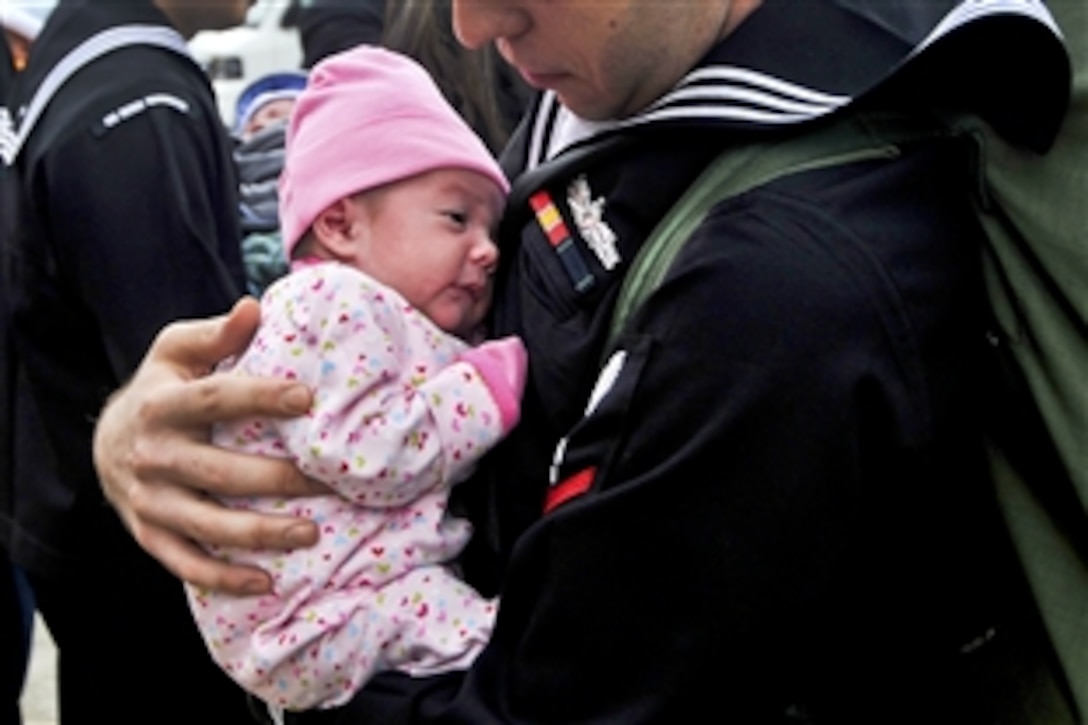 U.S. Navy Petty Officer 3rd Class Matthew Sandlin holds his newborn daughter for the first time after being under way for six months aboard the aircraft carrier USS George Washington in the Pacific Ocean, Nov. 1, 2010. Sandlin is a machinist's mate.