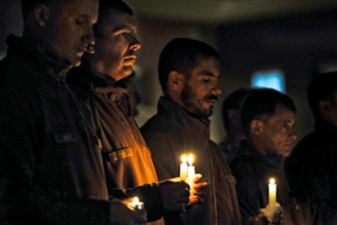 Coalition members from the International Security Assistance Force Joint Command hold candles to remember fallen soldiers during the All Saints Day ceremony at Kabul International Airport, Afghanistan, Nov. 1, 2010.