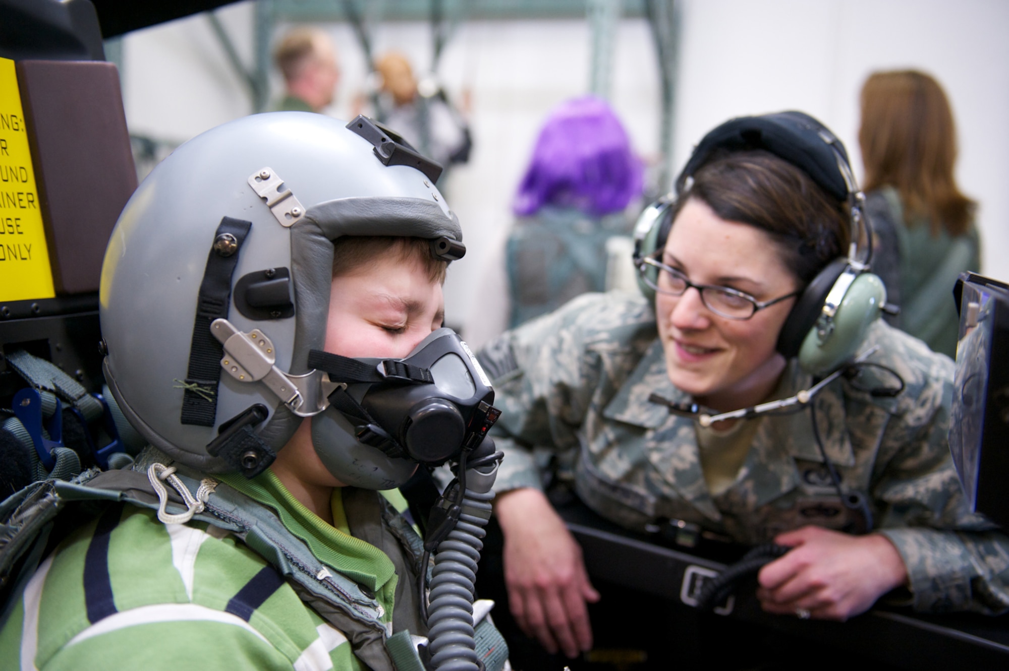 JOINT BASE ELMENDORF-RICHARDSON, Alaska - Keegan Hall, 12, breathes through an oxygen mask, Oct. 29, in the F-22 Raptor egress procedure trainer with the help of Tech. Sgt. Chelsea De La Fuente, Aircrew Flight Equipment Flight, 3rd Operations Support Squadron.  (U.S. Air Force photo/David Bedard)