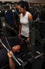 MINOT AIR FORCE BASE, N.D. -- Airman Ian Carrion, 5th Operations Support Squadron air crew flight equipment, warms up as Airman 1st Class Monica Diaz De Lope-Diaz, 5th OSS air crew flight equipment, spots him before starting his weight lifting routine at the McAdoo Sports and Fitness Center here Nov. 3. It is important to ensure an ample amount of strength training is incorporated into time spent at the gym. (U.S. Air Force photo by Airman 1st Class Aaron-Forrest Wainwright)