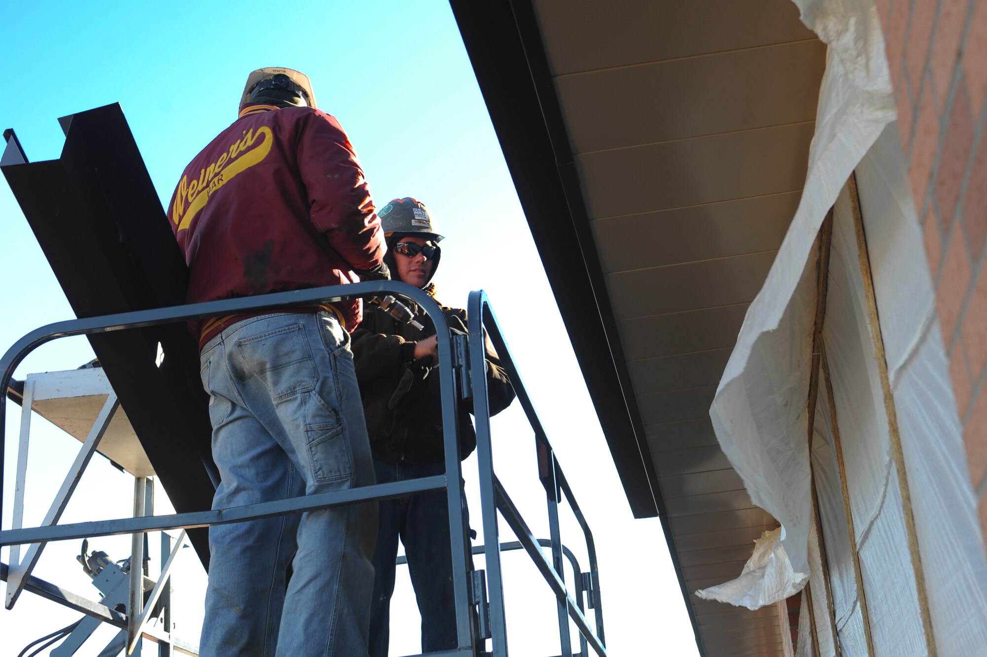 MINOT AIR FORCE BASE, N.D. -- Contractors Dustin Betzman and Lance Truax, install roof panels and gutters to the breezeway being built between the Commissary and Exchange here Nov. 3. The breezeway will help protect customers from harsh weather during the winter months as they transit from one building to the other. Construction on the breezeway is projected to be finished by the end of November. (U.S. Air Force photo by Airman 1st Class Aaron-Forrest Wainwright)