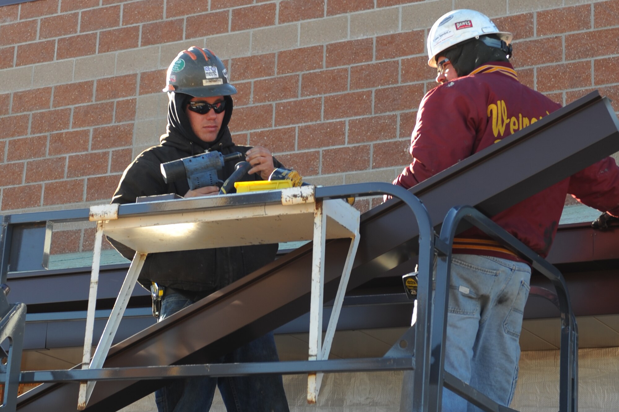 MINOT AIR FORCE BASE, N.D. -- Contractors Dustin Betzman and Lance Truax, install roof panels and gutters to the breezeway being built between the Commissary and Exchange here Nov. 3. The breezeway will help protect customers from harsh weather during the winter months as they transit from one building to the other. Construction on the breezeway is projected to be finished by the end of November. (U.S. Air Force photo by Airman 1st Class Aaron-Forrest Wainwright)