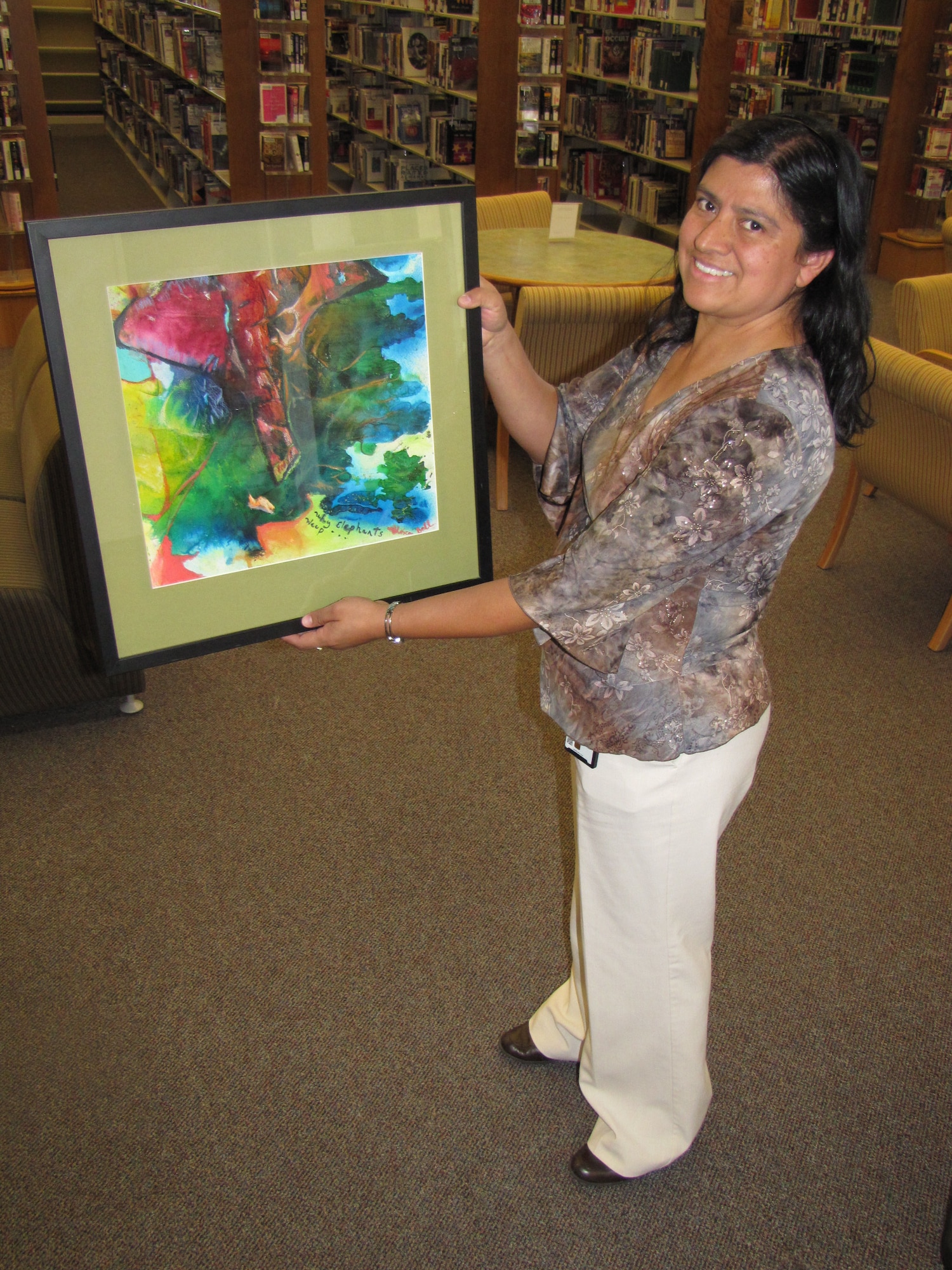 Alison Vásquez, Edwards Base Library supervisory
librarian, holds up a painting by Ricky Perkins, an artist who resides in
Lancaster, Calif. Several of Ms. Perkins’ artwork will be displayed at the
base library throughout November as the library runs its Local
Artists Showcase program, which began in October to encourage local artists
within the Antelope Valley to display their artwork for members of the
Edwards community to see. (U.S. Air Force photo by Staff Sgt. Angelique N.
Smythe)
