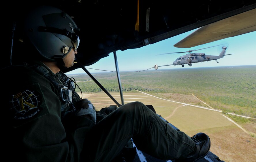 MOODY AIR FORCE BASE, Ga. -- Tech. Sgt. Rafael Orozco, 71st Rescue Squadron loadmaster, looks toward an HH-60G Pave Hawk from the 41st Rescue Squadron as it conducts an in-flight refueling during a combat search and rescue airpower demonstration here Oct. 29. Moody was celebrating the annual Flying Tigers Reunion and presented the CSAR demo to a number of veterans and retirees. (U.S. Air Force photo by Airman Class Joshua Green/RELEASED)
