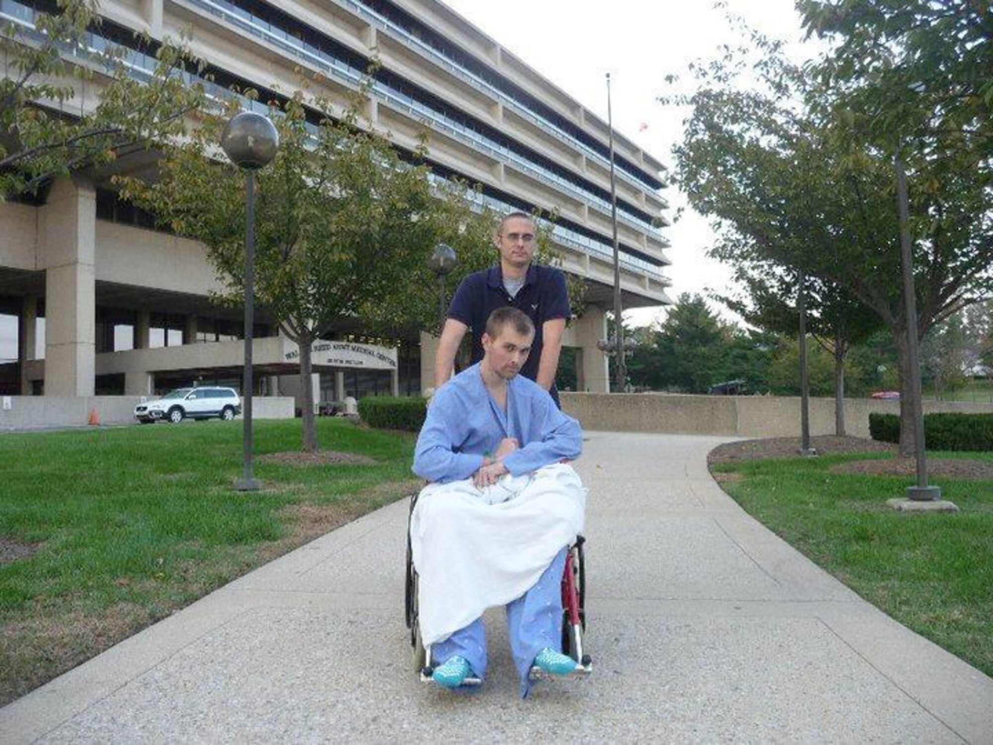 Senior Airman Erving Perkins wheels his wingman, Airman Colton Brown, out of Walter Reed Army Medical Center Oct. 8, 2010, for the first time while recovering from an illness. Shortly after arriving at Joint Base Balad, Iraq, fluid was found in Airman Brown's lungs, drainage tubes were placed and he was medically evacuated from the Air Force Theater Hospital to Germany. Airmen Perkins and Brown are both 4th Operation Support Squadron aircrew flight equipment technicians. (Courtesy photo)