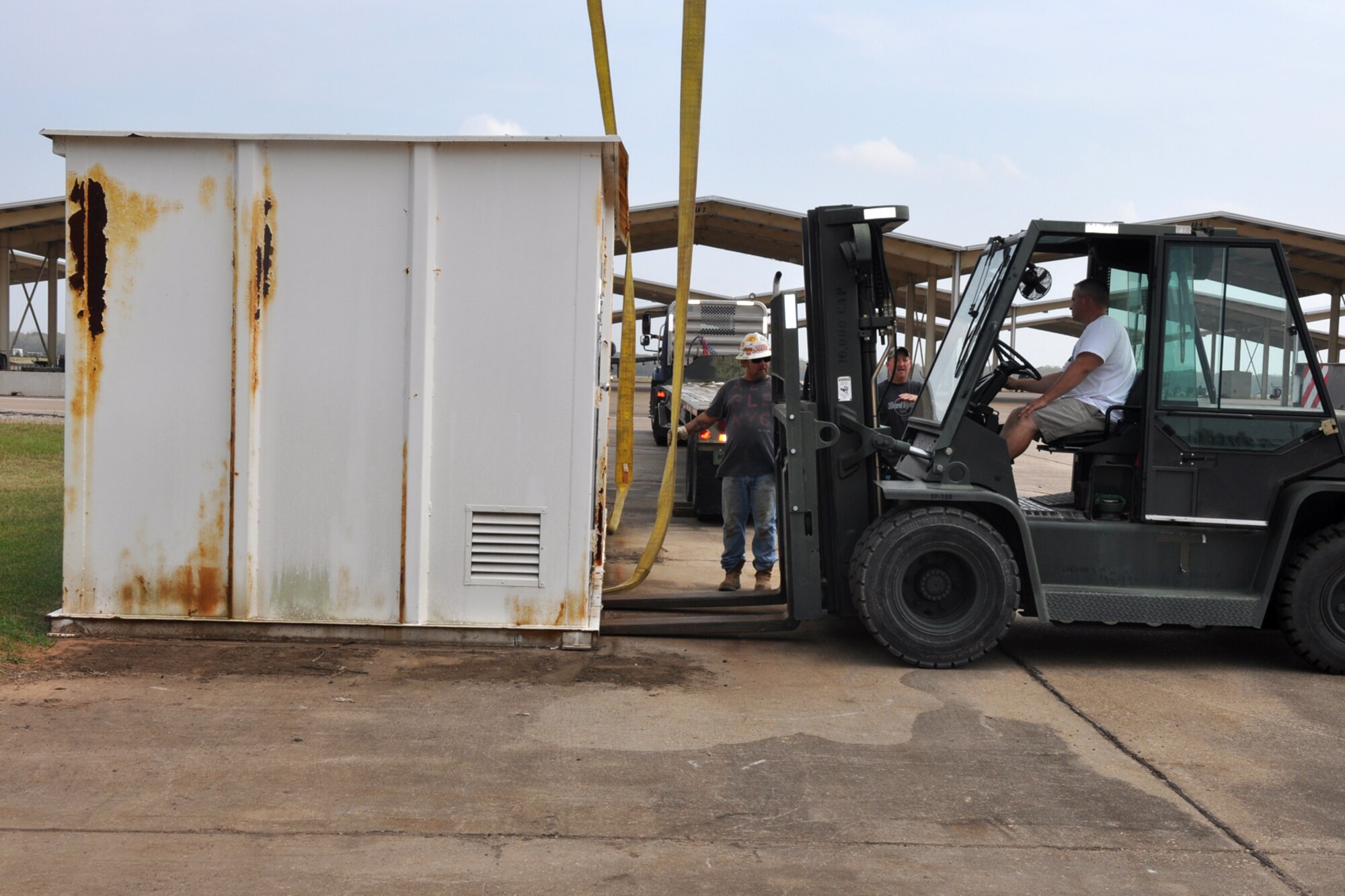 Workers prepare to pull load straps under a storage container before a crane lifts it onto a flat-bed trailer near the 917th Maintenance Squadron’s Metals Technology building on Barksdale Air Force Base, La., Oct. 22, 2010. Due to the every changing world of technology and advances in fabrication equipment, the 917th Wing is expanding the present structure by adding additional work space to the first floor and office spaces to the second floor. The shop deals with the fabrication of aircraft parts or air ground equipment for the 917th Wing. The addition of the advanced equipment will give greater capabilities to the shop to accomplish their mission. (U.S. Air Force photo/Betty Stephens) 