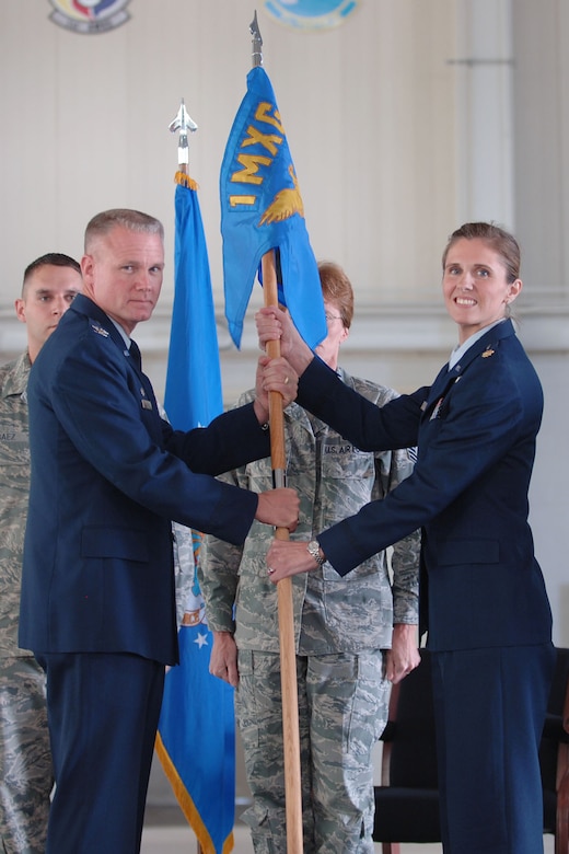 LANGLEY AIR FORCE BASE, Va. -- Col. George Zaniewski (left), 1st Maintenance Group commander, presents the 1st Maintenance Squadron unit guidon to Maj. Elizabeth Boehm, the squadron’s new commander, during the 1st Component Maintenance Squadron inactivation and 1st Equipment Maintenance Squadron re-designation ceremony at the 149th Fighter Squadron Hangar Oct. 29. Major Boehm served as the 1st Component Maintenance Squadron’s last commander before its inactivation, and assumed command of the newly-re-designated squadron from Lt. Col. Jason Gibson. (U.S. Air Force photo/Airman 1st Class Jason J. Brown) (RELEASED)