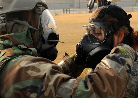 KUNSAN AIR BASE, Republic of Korea -- An Airman is assisted in the removal of her gas-mask at the contamination control area here during exercise Beverly Midnight 10-05, Nov. 5, 2010. Removing contaminated equipment is a task completed in the CCA by going through a set-by-step process of removing equipment. (U.S. Air Force photo/Senior Airman Ciara Wymbs)