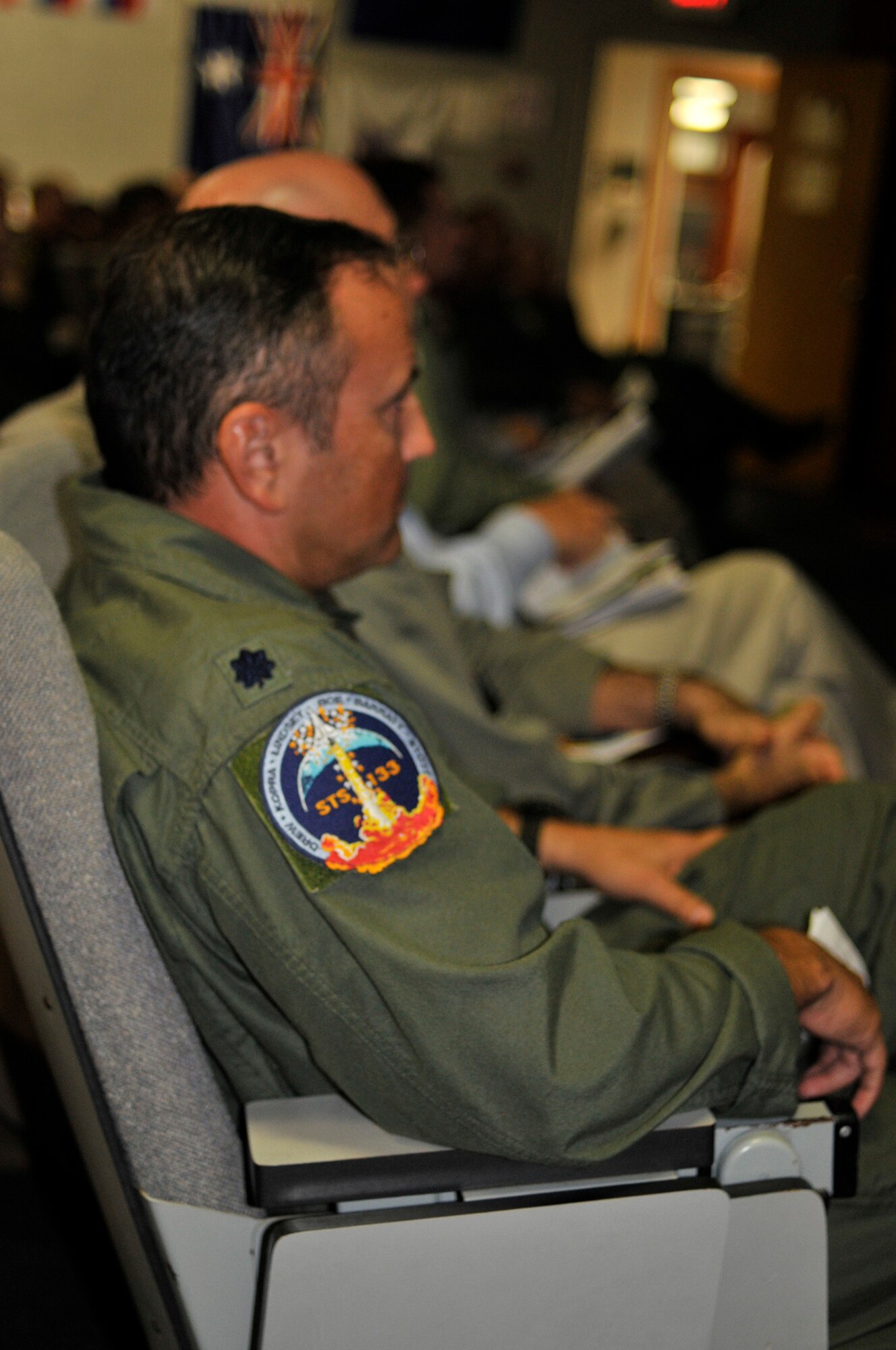 PATRICK AIR FORCE BASE, Fla. - Lt. Col. Lars Ulissey, 45th Space Wing Chief of Bioastronautics, Det. 3, Medical Division, along with nearly 100 servicemembers from all five branches, listens during the Shuttle Joint Task Force in briefing, at the 301st Rescue Squadron here Nov. 2 to prepare those who are here supporting the emergency portion of the space shuttle Discovery launch Nov. 5. It's the last launch of Discover and the third to the last space shuttle launch.  Shown on Lt. Colonel Ulissey's shoulder is the NASA patch made especially for this launch. (U.S. Air Force photo/Capt. Cathleen Snow)