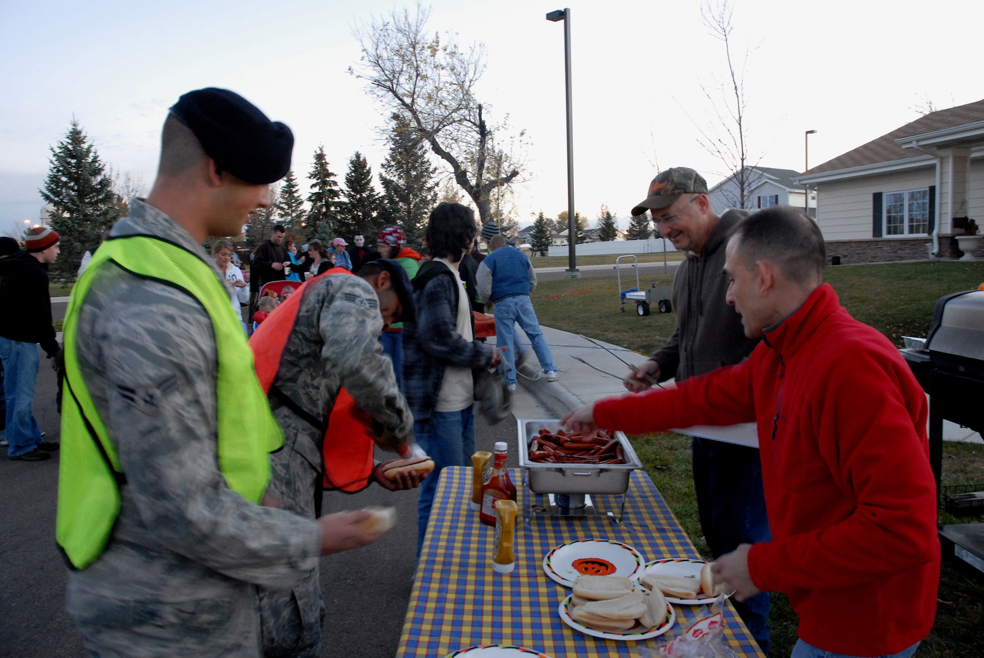 From left, Airman 1st Class Grant Uhrich  and Senior Airman Jonathan Walker, both from the 341st Security Forces Squadron Tactical Response Force, and "Pumpkin Patrol" volunteers are served hot dogs by Col. Jeffrey Frankhouser, 341st Maintenance Group commander, and Col. John Patricola, 341st Mission Support Group commander outside the home of Col. Anthony Cotton, 341st Missile Wing commander Halloween night. The two TRF members patrolled base housing to ensure the safety of Malmstrom trick-or-treaters. (U.S. Air Force photo/Staff Sgt. Dillon White)