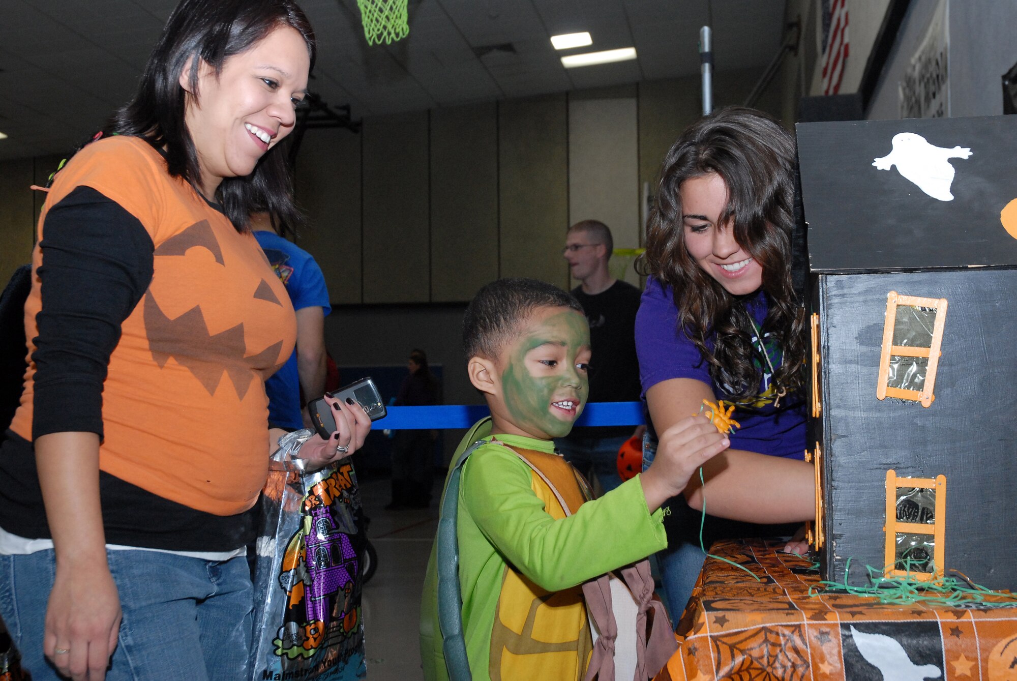 Toni Kelly watches her 4-year-old son, Payton, pull a toy from a "haunted house," at the Youth Center's Fall Festival Oct. 29 after Darrian McManious, event volunteer, convinced him it was safe. (U.S. Air Force photo/Staff Sgt. Dillon White)