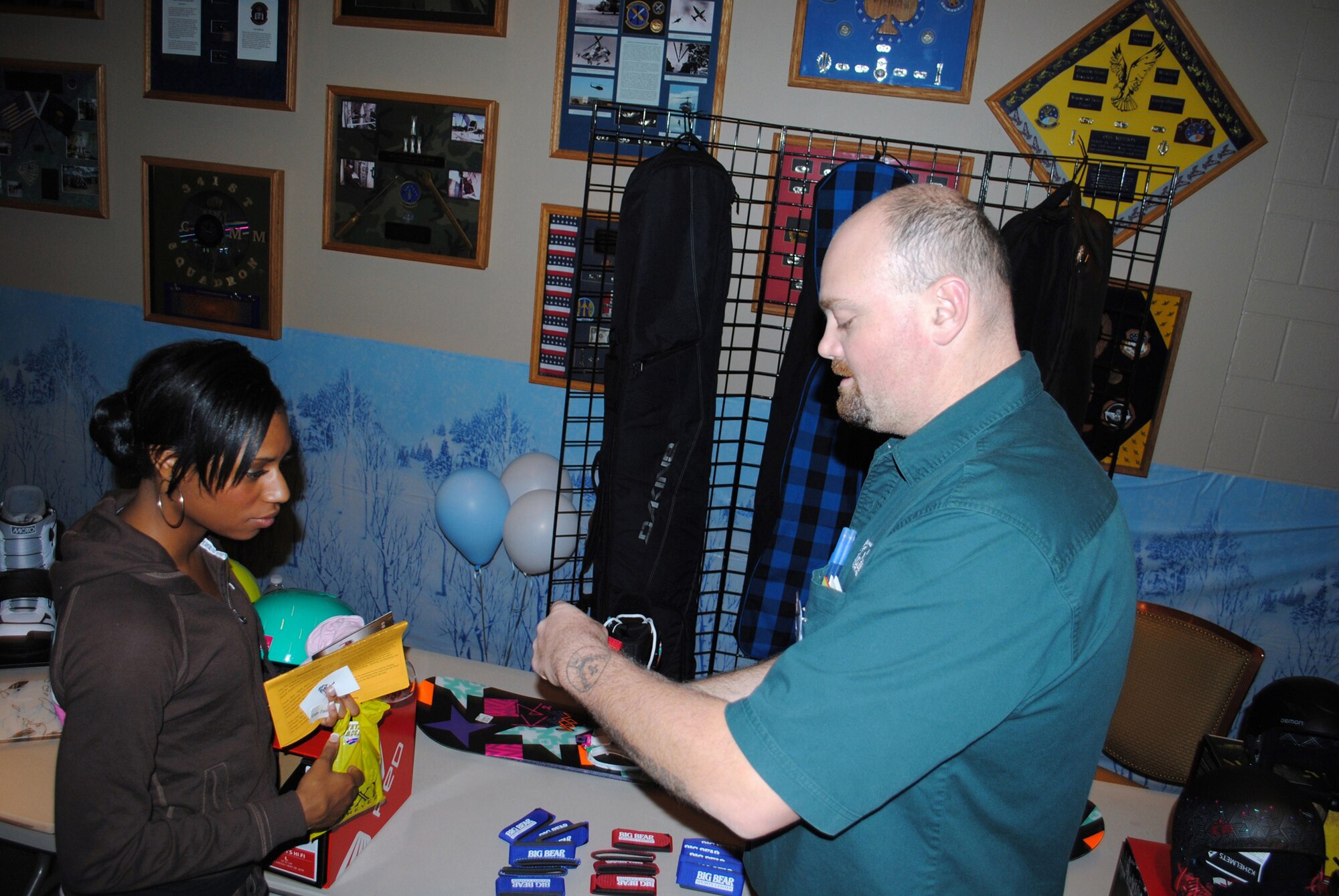 Doug Nordlund, a Big Bear Sports Center sales representative, shows Senior Airman Dynesha Adams, 341st Force Support Squadron promotions technician, some of the new Ski/Snowboard safety equipment available for the snow season Oct. 28. (U.S. Air Force photo/Airman 1st Class Kristina Overton)