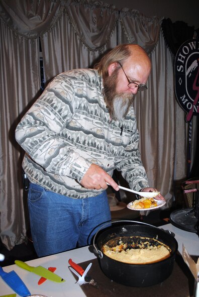 Bob Dowdy, founder of Dutch Oven Delights, scoops a plateful of his Dutch oven-made Sparkling Peach Cobbler for a guest at the Annual Ski Expo and Dessert and Wine Fair at the Grizzly Bend Club. (U.S. Air Force photo/Airman 1st Class Kristina Overton)