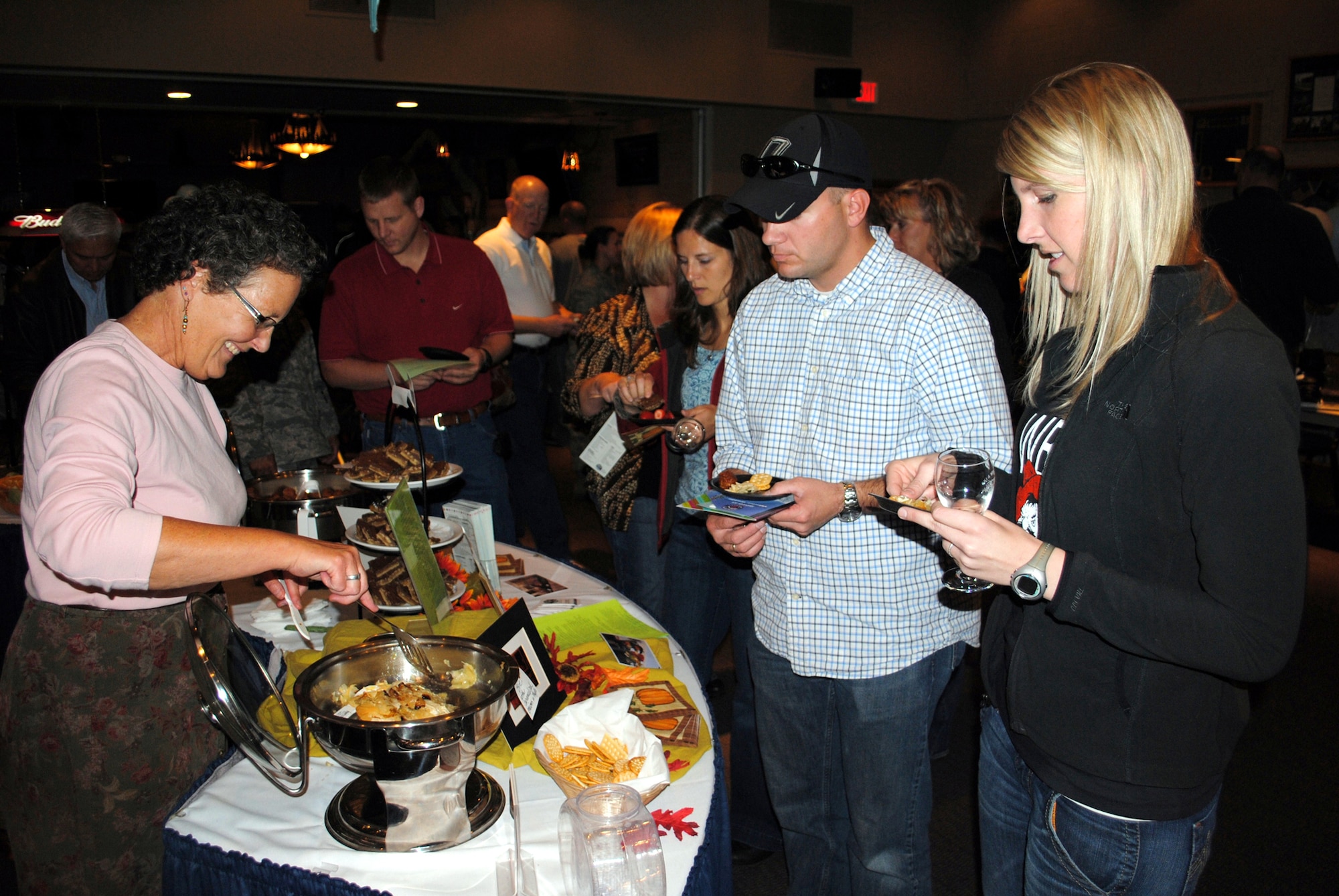 Penny Rubner, owner of Penny’s Gourmet To Go, prepares to  plate some of her hors d'oeuvres for 1st Lt. Karrie Wray, 341st Operations Support Squadron ICBM deputy combat commander, and Tech Sgt. Jeremy Wray, 341st Civil Engineer Squadron firefighter at the Annual Ski Expo and Dessert and Wine Fair Oct. 28. (U.S. Air Force photo/Airman 1st Class Kristina Overton)