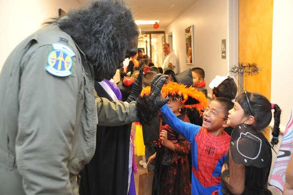Capt. Jack Lovin, SDTW, dressed as an Air Force gorilla, gives student Omar Roque a high five as he and his classmates from Kirtland Elementary trick or treat.